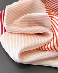 Macro shot of striped faux silk fabric with glossy texture and elegant orange-red folds