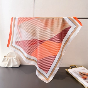 Detailed drape of geometric printed silk scarf with vibrant orange and pink patterns