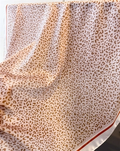 Close-up of leopard print silk scarf featuring red borders and smooth satin texture