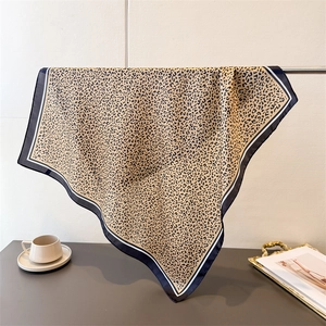 Close-up of leopard print silk scarf with contrast black border and elegant draping