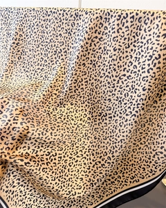 Detail of leopard print silk scarf featuring fine texture and striped border edges