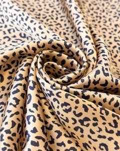 Macro shot of silk-like leopard print fabric with golden brown texture and soft draping