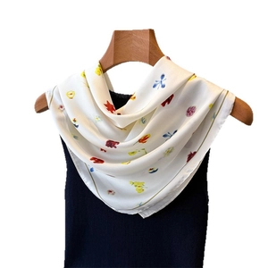 Foulard en soie à fleurs porté sur un haut en tricot noir sur fond blanc