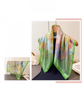 Detail of vibrant floral print silk square scarf with green and orange abstract patterns
