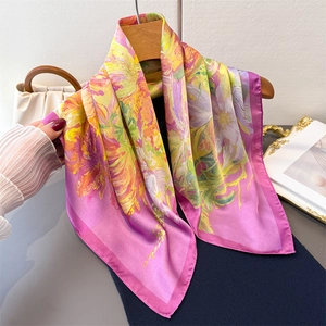 Elegant floral print silk scarf in pink and purple tones hanging on a wooden hanger