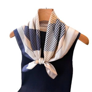 Elegant geometric stripe printed silk square scarf styled on a wooden hanger with a vest