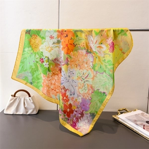 Détail d'un foulard carré en soie avec imprimé floral de peinture à l'huile et bord jaune
