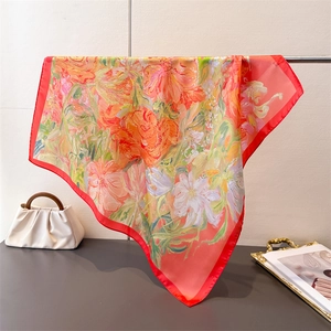 Detail of silk-like satin square scarf with bright floral print and red borders