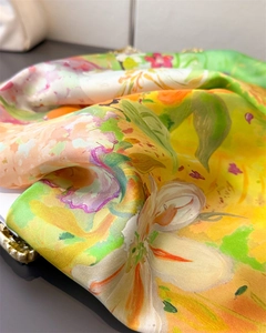 Gros plan d'un foulard carré en soie avec d'élégants imprimés de fleurs de lys jaunes