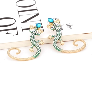 Macro shot of green enamel gecko earrings with sparkling crystals and gold finish