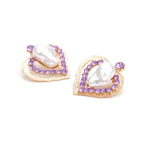 Dettaglio di orecchini a cuore dorati con strass viola e perla barocca