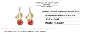 Détail de boucles d'oreilles cerise avec strass rouges, perles et alliage de zinc doré