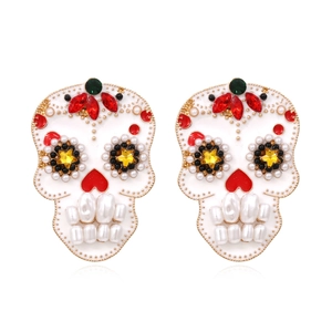 Orecchini a teschio con cristalli colorati e denti di perle su sfondo bianco neutro