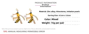 Detailed view of enamel bee earrings with rhinestones and pearls on white background