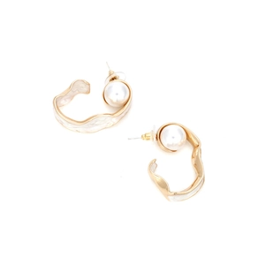 Detail view of gold alloy C-shape earrings with white enamel and large pearl inlay