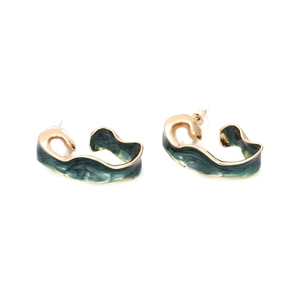 Detail view of twisted gold alloy C-shape earrings with green enamel and white pearl accents