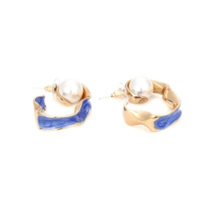 Detailed view of C-shaped gold earrings with blue marble enamel and white pearl accents