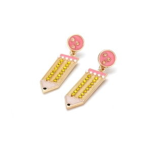Détail de boucles d'oreilles en forme de crayon avec strass jaunes et perles