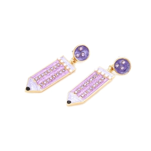 Détail de boucles d'oreilles crayon en émail violet avec strass et base dorée