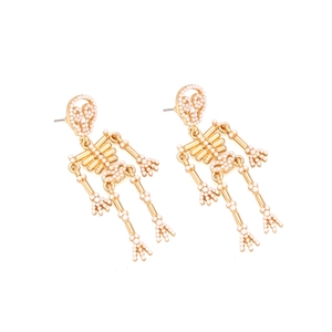 Detailed macro view of golden alloy skeleton earrings with embedded faux pearl accents
