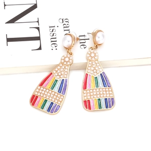 Detail of bohemian gold earrings with colorful enamel stripes and white pearl accents