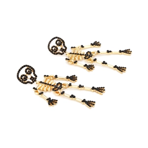 Boucles d'oreilles tête de mort gothiques dorées avec strass noirs sur fond blanc