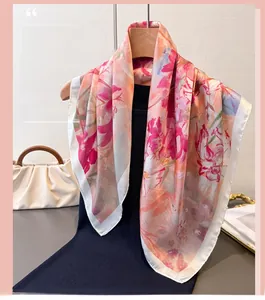 Dettaglio di sciarpa in seta a fiori rosa e corallo appesa a una gruccia in legno