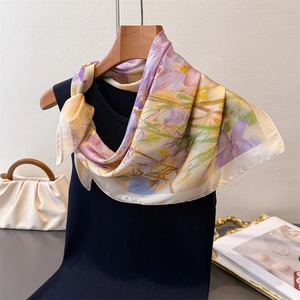 Dettaglio ravvicinato di foulard in seta a fiori indossato su un gilet nero con accessori