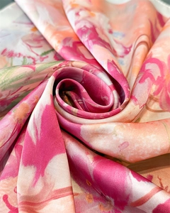 Dettaglio macro di una sciarpa in seta con texture liscia e motivi floreali rosa