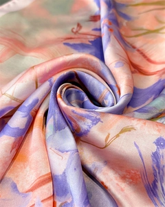 Dettaglio macro del tessuto foulard in seta con motivi floreali astratti sfumati rosa e arancio