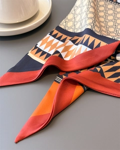 Close-up of geometric pattern silk scarf with warm orange tones and coffee cup background