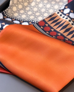 Detailed close-up of glossy satin silk scarf showing geometric diamond patterns and texture