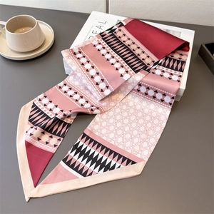 Macro detail of geometric print silk scarf with pink and black patterns on a dark table