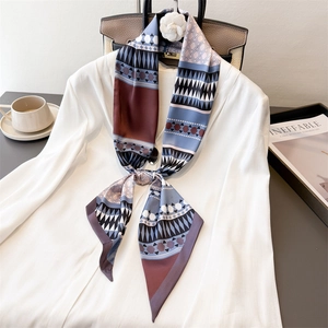 Elegant geometric patterned neck scarf styled on a white blazer with a camellia brooch