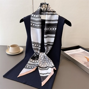 Detail of silk scarf with geometric pattern and camellia brooch on navy vest