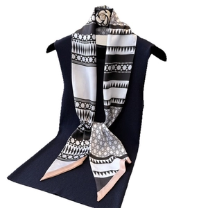 Fashionable geometric black and white silk scarf with pink trim on a navy blue top
