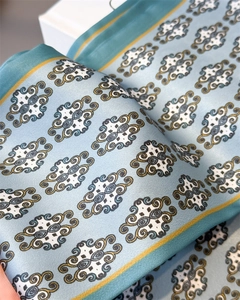 Detailed macro view of light blue silk scarf with classic pattern and vibrant borders