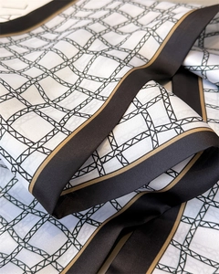 Gros plan d'un foulard en soie à carreaux montrant la texture lisse et le bord doré