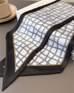 Détail d'un foulard en soie à carreaux géométriques avec bordure noire et liseré doré