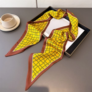 Gros plan d'un foulard en soie jaune à carreaux noirs sur un plateau décoratif noir