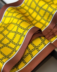 Gros plan du foulard en soie avec motifs géométriques jaunes et bordures marron