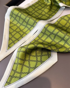 Détail d'un foulard en soie vert sauge à motif de grille géométrique et lustre satiné
