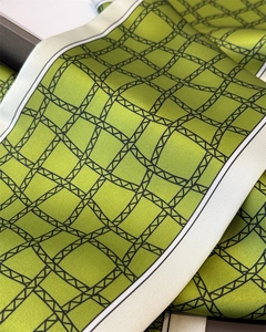 Gros plan du foulard en satin vert avec grille géométrique noire et texture lisse et douce