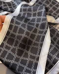 Détail d'un foulard en soie à carreaux géométriques avec texture lisse et bord blanc