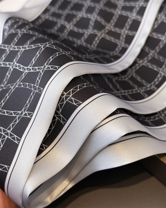 Détail d'un élégant motif géométrique noir et blanc sur le tissu lisse d'un foulard en soie