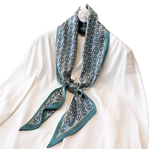 Elegant teal silk scarf with vintage floral patterns and gold trim on white shirt
