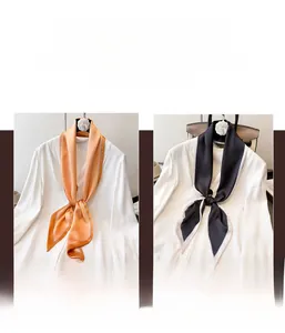 Detail of satin skinny scarf with contrast border and camellia floral brooch accessory
