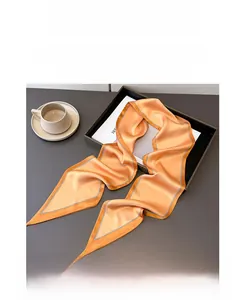 Macro view of bright orange satin skinny scarf on tray with coffee cup decor