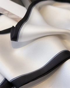 Close-up of silk scarf fabric showing smooth white satin texture and black border detail