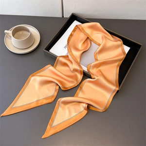 Close-up of bright orange satin silk scarf with elegant black and white border piping